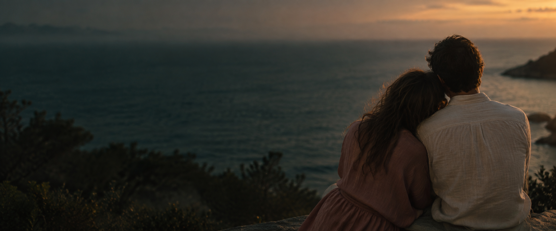 Two people leaning together beside the sea at dusk